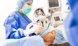 Dentist performing sleep dentistry procedure on patient in modern dental operatory.